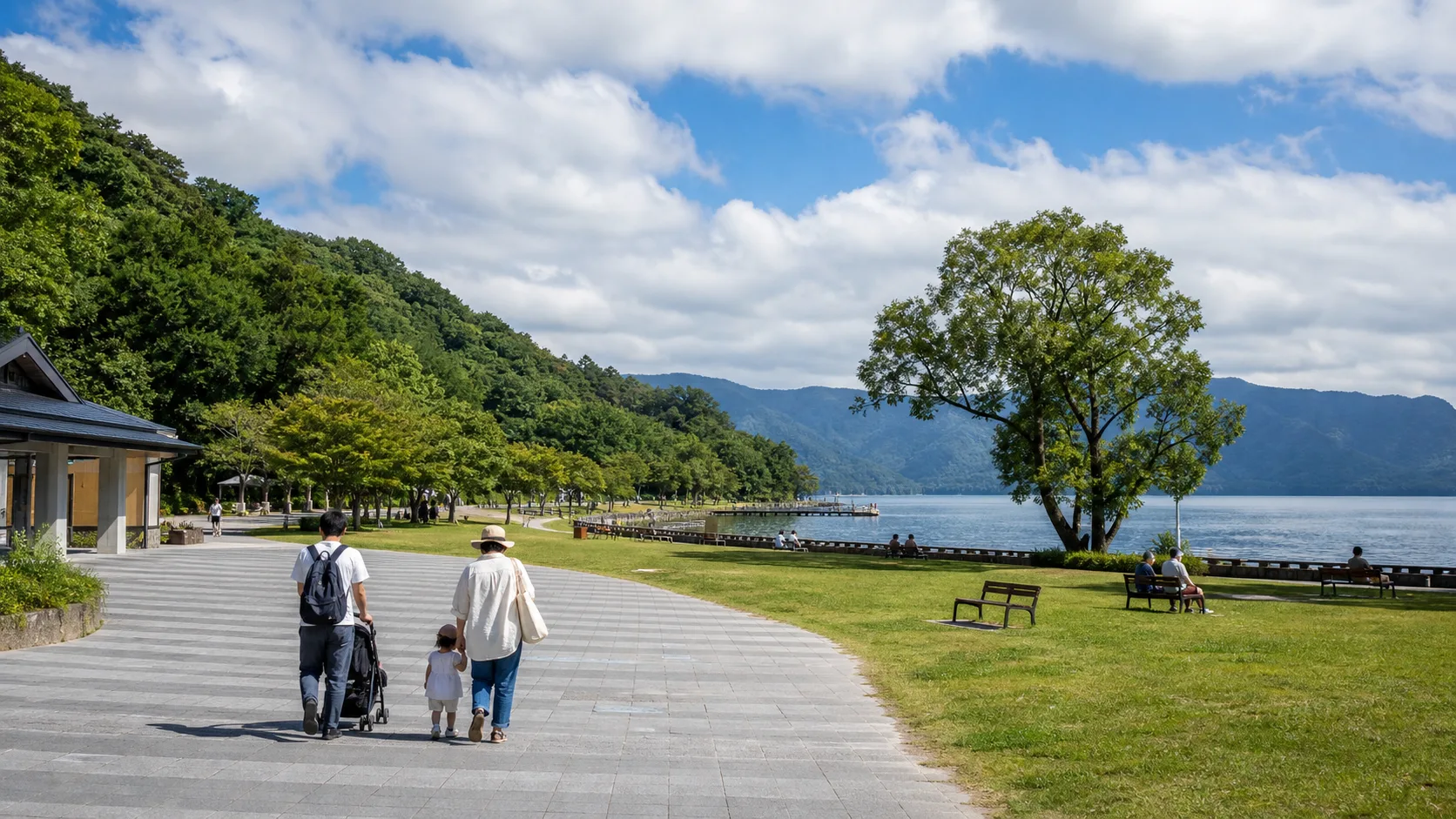 十和田湖畔の広い歩道と芝生で家族が休むイメージ写真