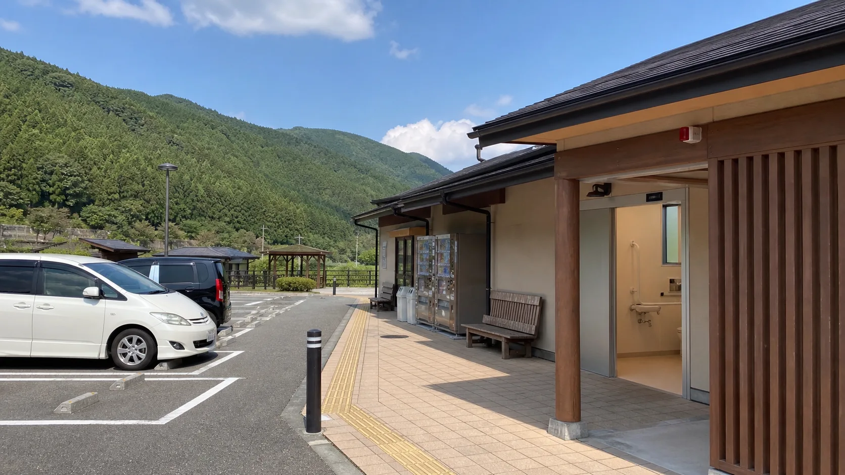 駐車場、トイレ、ベンチがまとまった山あいの休憩施設のイメージ写真