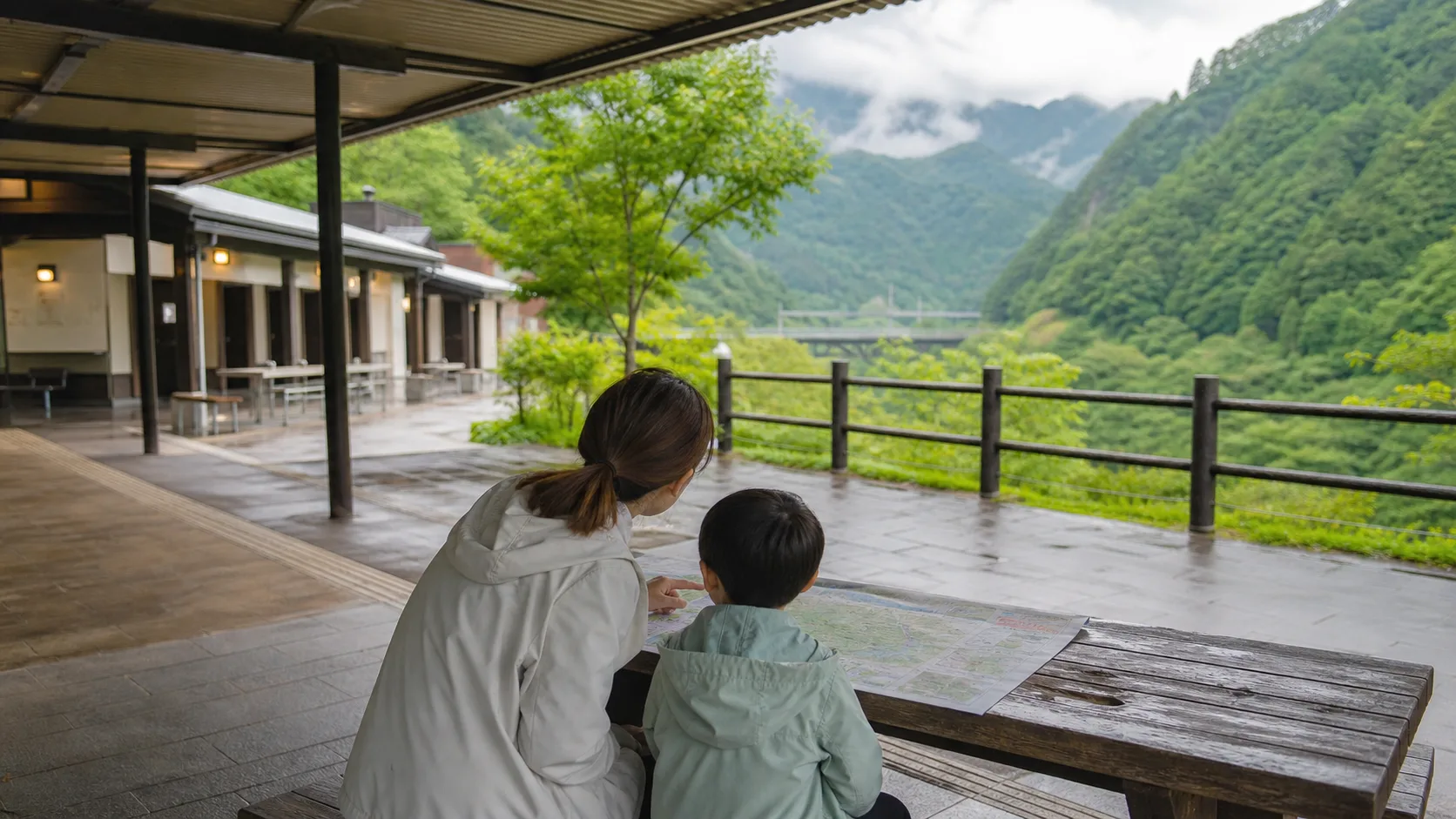 雨上がりの屋根付き休憩場所で親子が地図を見ながら高千穂観光を考えるイメージ写真